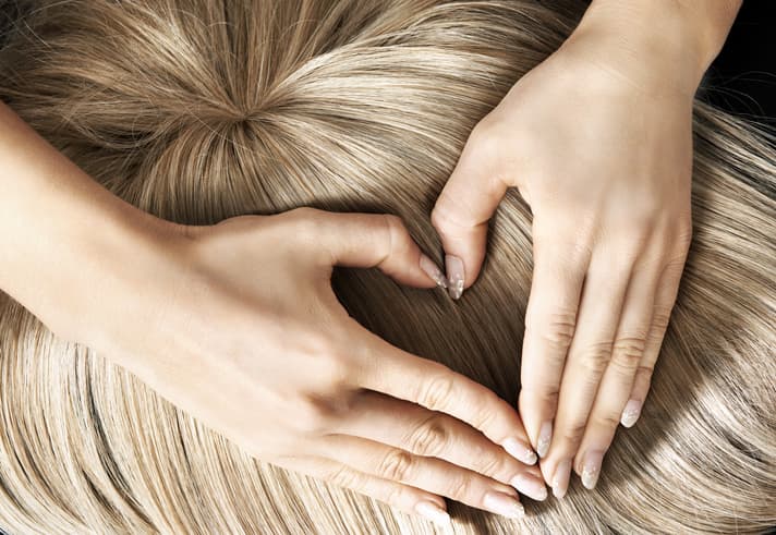 Perücke darüber eine Hand zu einem Herz geformt