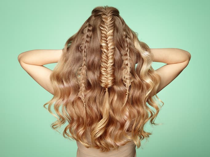 Frau mit langen blonden Haaren mit Zöpfen von hinten
